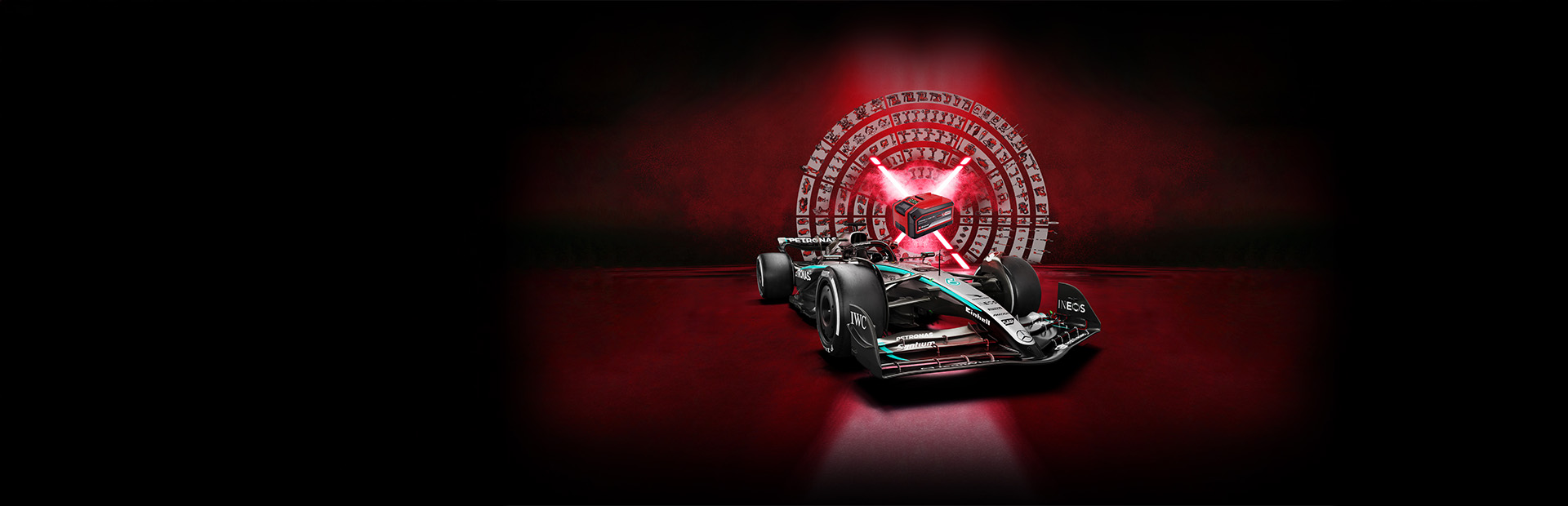 Un carro de carreras de Fórmula 1 Mercedes-AMG PETRONAS delante de un fondo rojo con una batería Einhell Power X-Change en el centro iluminada por rayos de luz rojos.