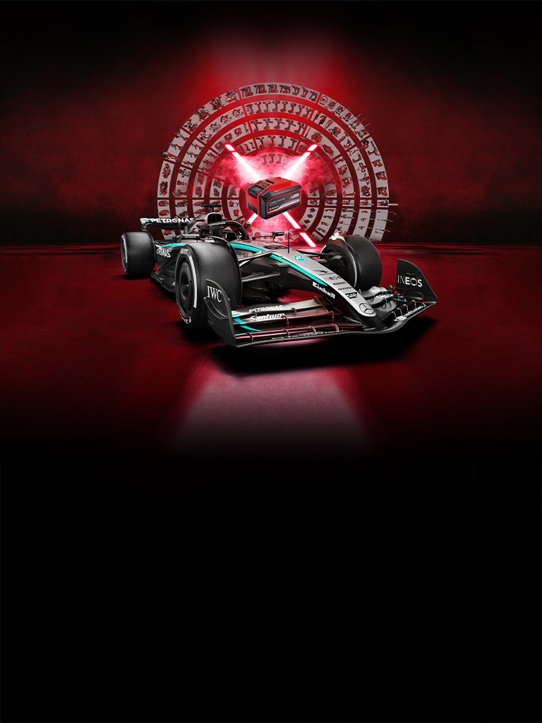 Un carro de carreras de Fórmula 1 Mercedes-AMG PETRONAS delante de un fondo rojo con una batería Einhell Power X-Change en el centro iluminada por rayos de luz rojos.