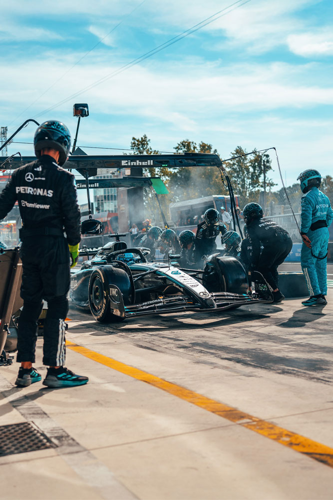 Una parada en boxes intensa para el equipo Mercedes-AMG PETRONAS Formula One. El equipo está en plena acción, cambiando neumáticos y revisando el auto bajo la estructura con el logo de Einhell.